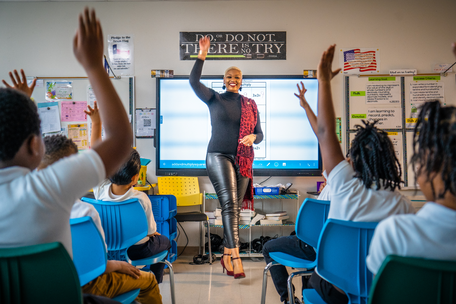 Taji teaching a math lesson with students raising hands